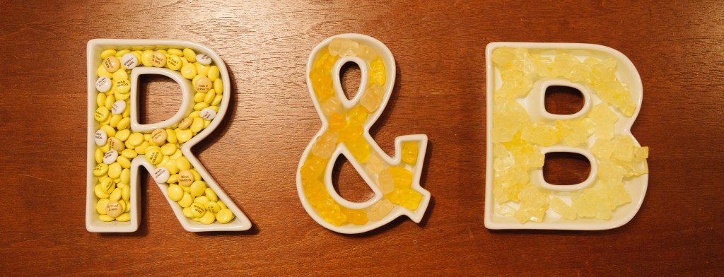 A photograph of R & B made of white porcelain candy dishes, filled with yellow candies.